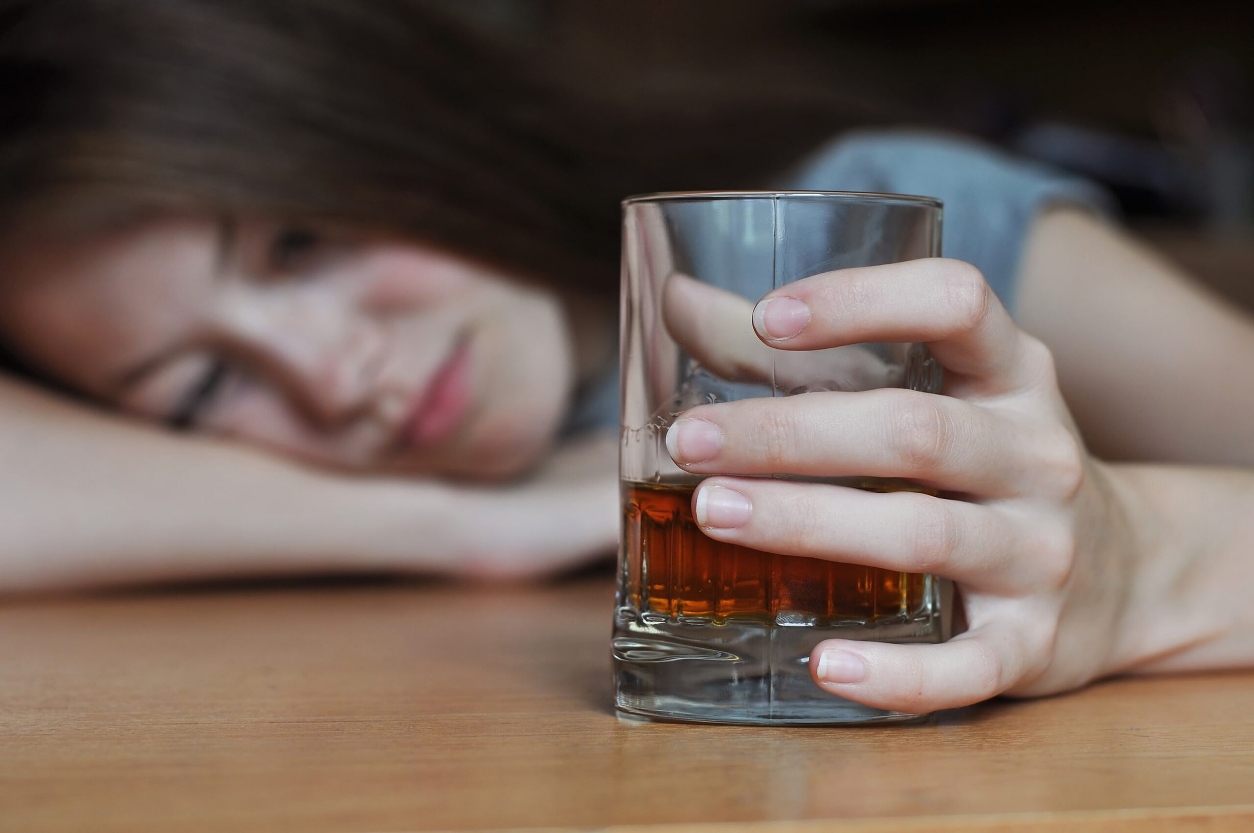 woman who is addicted to alcohol clutches a drink