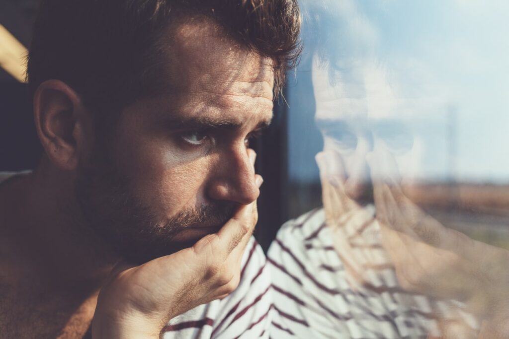 lonely man with low self-esteem looks out a window
