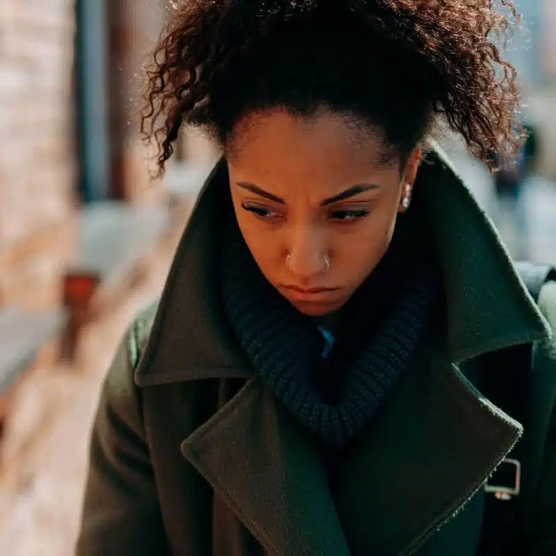 Woman in coat contemplating the consequences of her substance abuse.