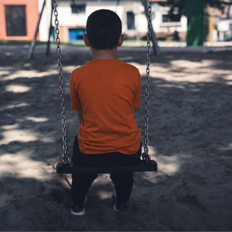 neglected child alone on swing set experiences childhood trauma